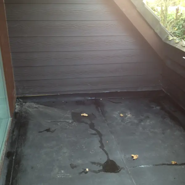 Toiture plate en roofing avec relevés contre un bardage