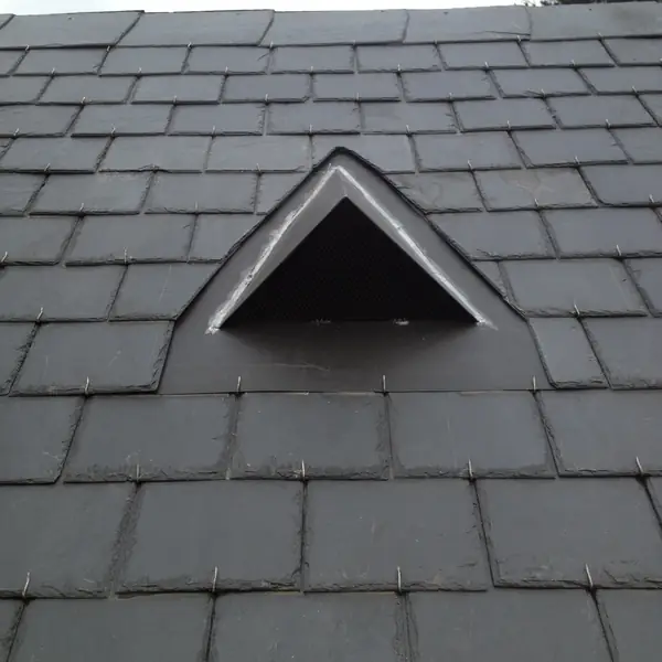 Outeau triangulaire sur une toiture en ardoises