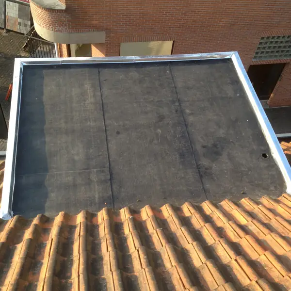 Toiture plate en roofing avec rives en zinc au-dessus d'une toiture en tuiles