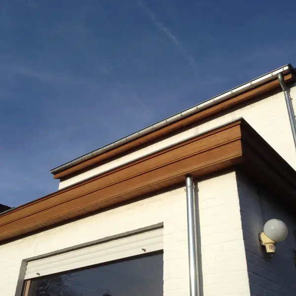 Corniche en bois et gouttière sur une maison enduite