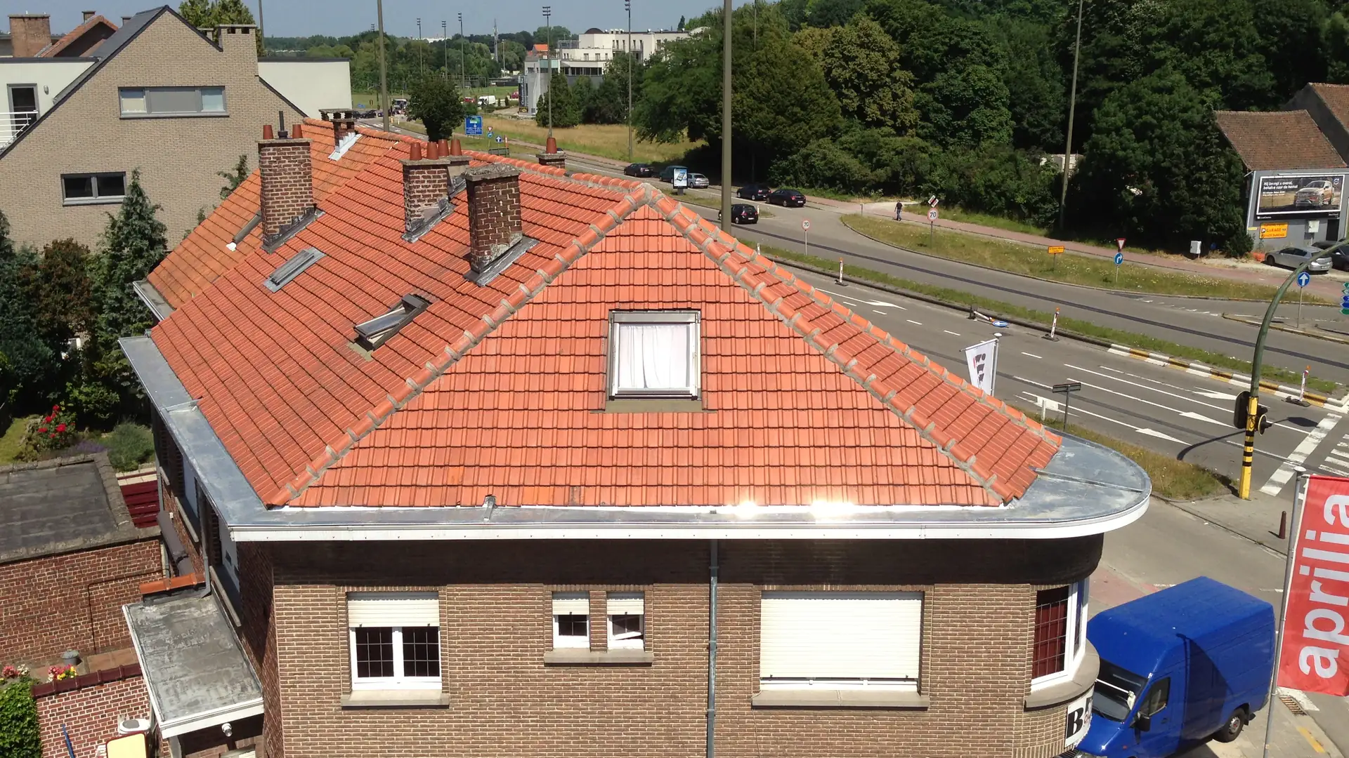 Toiture en tuiles rouges rénovée sur une maison d'angle
