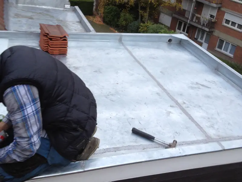 Couvreur posant une couverture en zinc sur une toiture plate